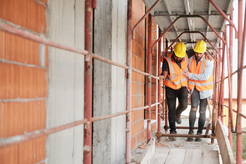 Manual Worker Helping Injured Colleague In Construction Site