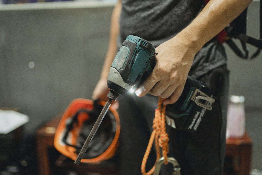 Contractor standing with working screwdriver and orange helmet